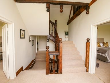 A carpeted staircase with wooden banisters between two open doors showing bedrooms at Shifford Manor Farm Shifford near Bampton Oxfordshire