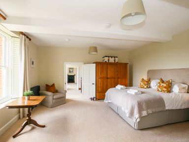 A bedroom with a double bed a wooden wardrobe an armchair and a small table with a plant at Shifford Manor Farm in Shifford near Bampton Oxfordshire