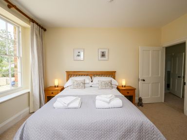 A bedroom with a double bed two bedside tables with lamps and a window at Shifford Manor Farm Shifford near Bampton Oxfordshire