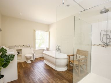 A bathroom with a freestanding bathtub a wooden chair a toilet a sink and a shower area at Shifford Manor Farm in Shifford near Bampton Oxfordshire