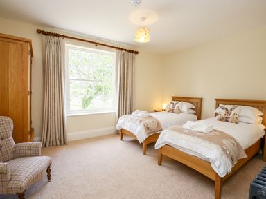 A bedroom with two single wooden beds with white bedding and animal cushions at Shifford Manor Farm Shifford near Bampton Oxfordshire