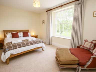 A bedroom with a double bed bedside tables a sofa and a large window at Shifford Manor Farm in Shifford near Bampton Oxfordshire