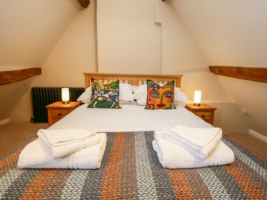 A bedroom with a bed with colorful pillows and folded towels on a blanket at Shifford Manor Farm in Shifford near Bampton Oxfordshire