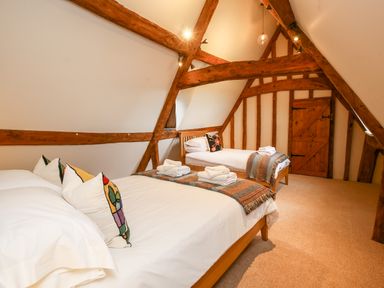 A bedroom with two beds and wooden beams at Shifford Manor Farm Shifford near Bampton Oxfordshire