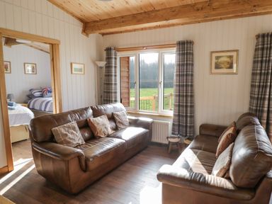 A living room with two brown leather sofas and plaid curtains at Top Style Orchard in Hallow