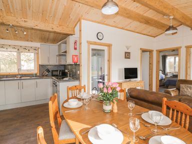 A kitchen and dining area with wooden table set for four and a living room with television at Top Style Orchard in Hallow
