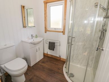 A bathroom with a toilet sink vanity mirror window radiator towel and curved glass shower at Top Style Orchard in Hallow