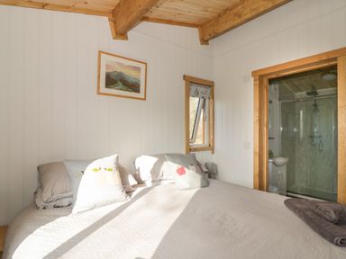 A bedroom with a bed pillows a wall painting an open window and a door leading to a bathroom at Top Style Orchard in Hallow