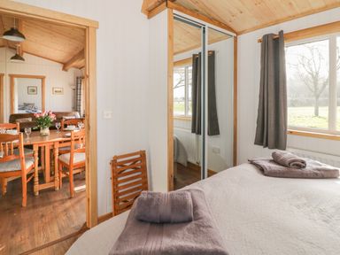 A bedroom with a bed and folded towels next to a window with curtains and a mirrored closet door at Top Style Orchard in Hallow