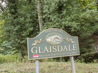 A welcome sign for Glaisdale village surrounded by trees and greenery