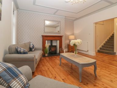 A living room with sofas and a coffee table by a fireplace and stairs in the background at Greenlawns in Burnham-On-Sea