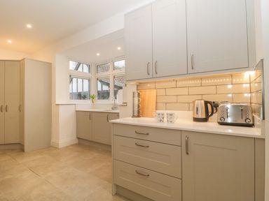 A kitchen with cabinets toaster kettle and two mugs on the counter at Greenlawns in Burnham-On-Sea