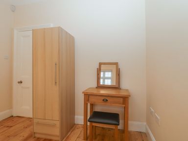 A wooden wardrobe and dressing table with mirror and stool in a room at Greenlawns in Burnham-On-Sea