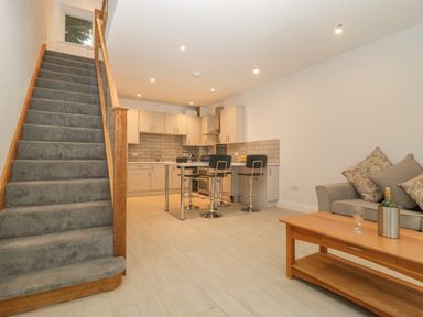 A kitchen and living area with staircase carpeted stairs and a wooden coffee table at Greenlawns in Burnham-On-Sea