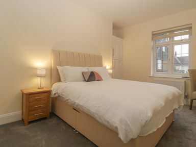 A bedroom with a double bed a bedside table with a lamp a window and a chair at Greenlawns in Burnham-On-Sea