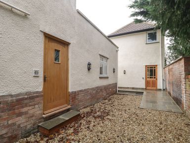 An outdoor area with two wooden doors stone steps gravel ground and brick and plaster walls at Greenlawns in Burnham-On-Sea