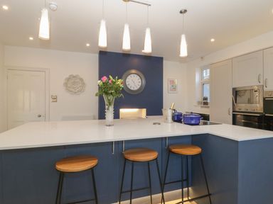 A kitchen with a large island and three wooden stools at Greenlawns in Burnham-On-Sea