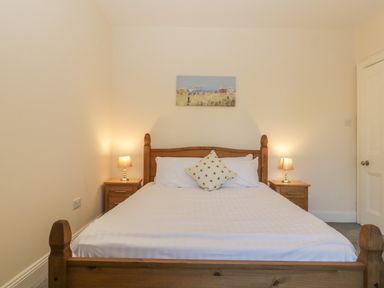 A bedroom with a wooden bed and two bedside tables with lamps at Greenlawns in Burnham-On-Sea