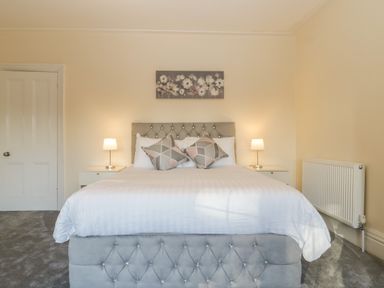 A bedroom with a large bed cushions and two bedside lamps at Greenlawns in Burnham-On-Sea