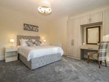 A bedroom with a bed a bedside table with a lamp built in wardrobe and a chair at Greenlawns in Burnham-On-Sea
