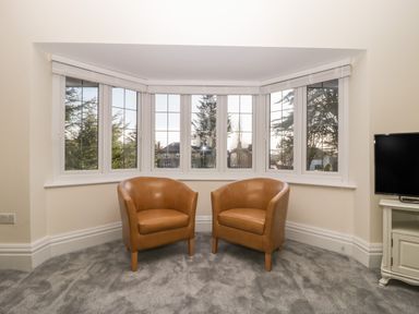 Two brown armchairs in front of a bay window in a living room at Greenlawns in Burnham-On-Sea