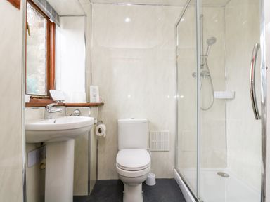 A bathroom with a sink a toilet and a shower with glass doors at Coach House Cottage in Bude