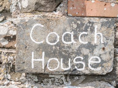 A stone sign with the text Coach House mounted on a brick wall at Coach House Cottage in Bude