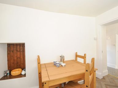 A wooden dining table with three chairs and cups on the table in a room at Lee Barton Farmhouse in Bude