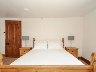 A bedroom with a wooden bed and side tables with lamps at Lee Barton Farmhouse in Bude