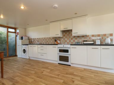 A kitchen with white cabinets a double oven a washing machine and countertop appliances at The Roundhouse in Bude
