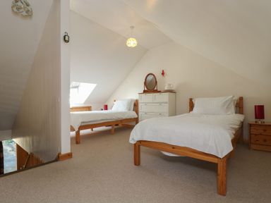 A bedroom with two single beds a dresser with a mirror and nightstands at The Roundhouse in Bude