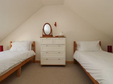 A bedroom with two single beds a white dresser with a mirror and a pitcher at The Roundhouse in Bude