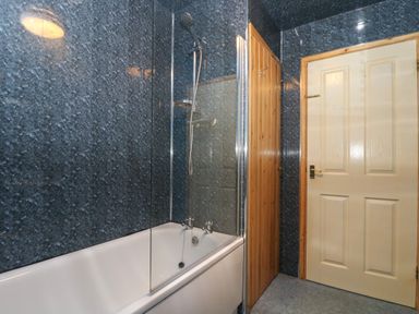 A bathroom with a bathtub shower combination and two doors at The Roundhouse in Bude