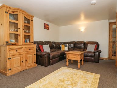 A living room with a brown leather sofa wooden cabinet and coffee table at The Wagon Linney in Bude