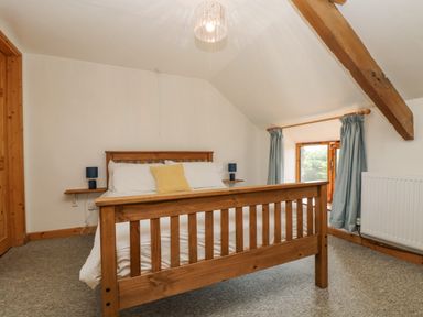 A bedroom with a wooden bed and blue lamps on wall shelves at The Wagon Linney in Bude