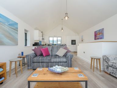A lounge area with a striped sofa and wooden coffee table in an open plan space at Devonair in Westward Ho