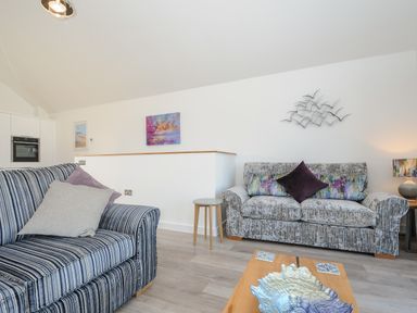 A living room with two sofas a coffee table and wall decorations at Devonair in Westward Ho