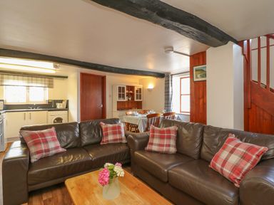 A living room with brown leather sofas and a wooden coffee table with flowers in a vase at The Stable in Bude