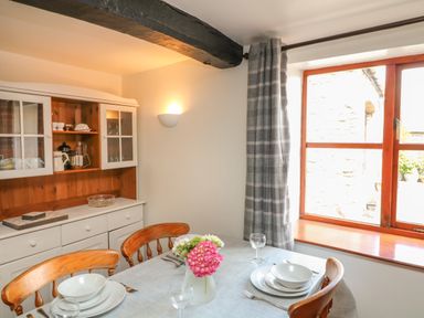 A dining area with a set table and a cabinet in the corner by a window at The Stable in Bude