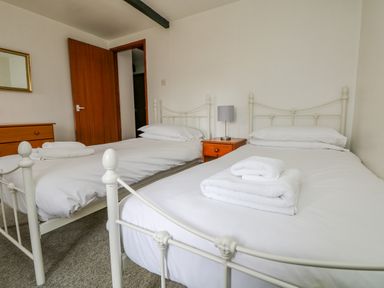 A bedroom with two single metal frame beds white bedding and folded towels at The Stable in Bude