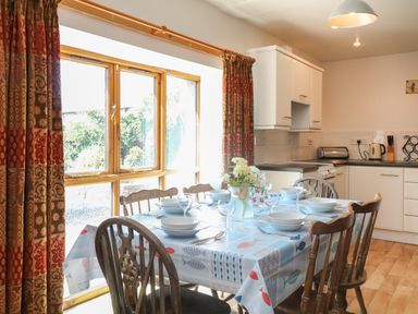 A dining table set with bowls and glasses near a window in a kitchen at The Dairy in Bude