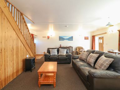 A living room with two black leather sofas a wooden coffee table and wooden staircase at The Dairy in Bude
