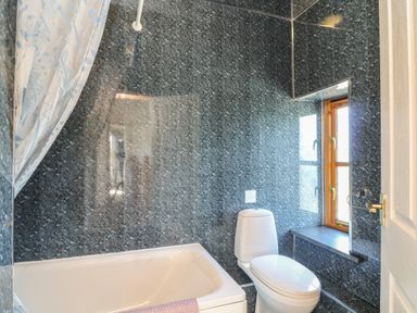A bathroom with a bathtub toilet and window at The Dairy in Bude