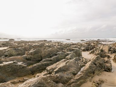 A rocky beach with sand and ocean waves at The Dairy in Bude
