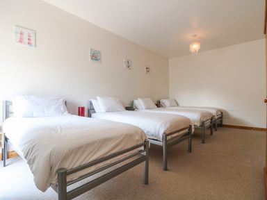 A bedroom with four single beds and nautical wall art at The Shippon in Bude