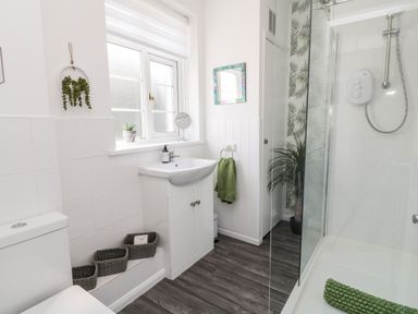 A bathroom with a toilet sink with cabinet shower area and baskets on the floor at Martingale in Torquay