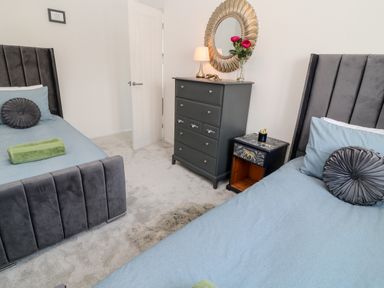 A bedroom with two single beds a chest of drawers a bedside table and a wall mirror at Martingale in Torquay