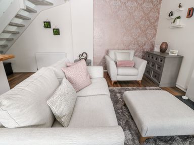 A living room with two light sofas a gray chest of drawers and floating shelves at Martingale in Torquay