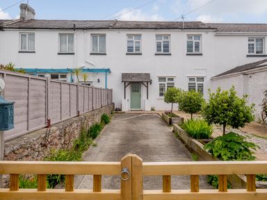 A front yard with a concrete driveway and plants leading to a white house with a green door at Martingale in Torquay