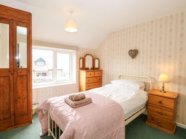 A bedroom with a single bed bedside table with lamp wooden wardrobe and chest of drawers at Primrose Cottage in Stiffkey